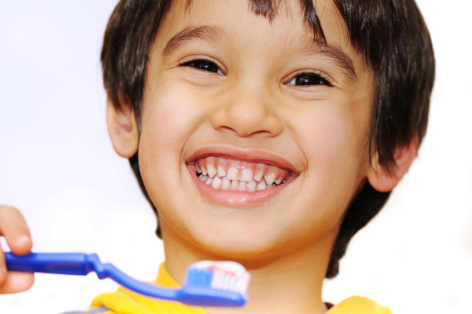 A smiling young boy holding a toothbrush